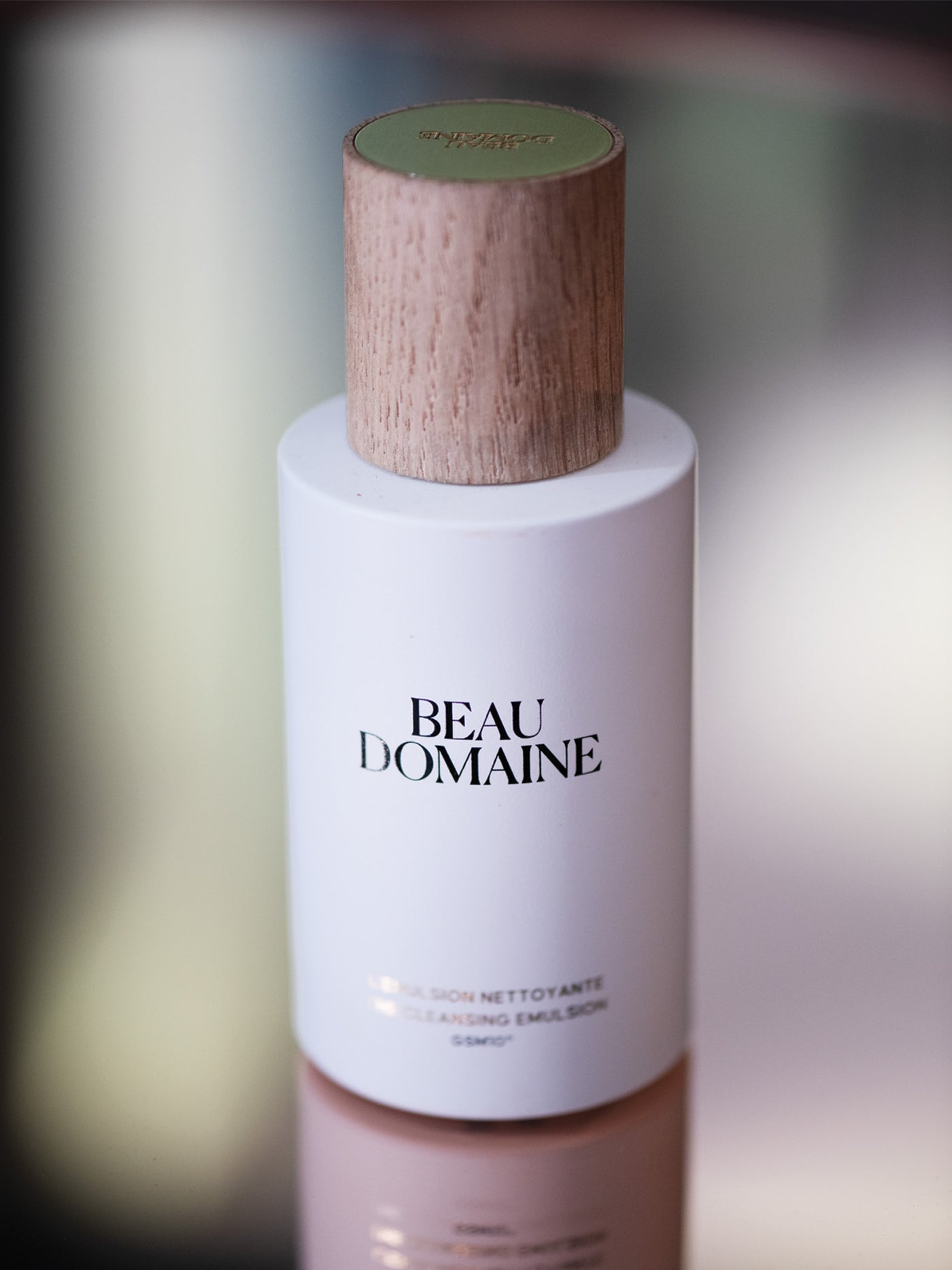 Flacon de Soins Beau Domaine avec bouchon en bois sur fond flou.